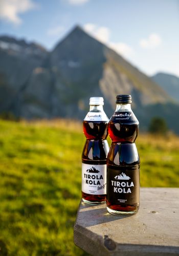 Glasflaschen Tirola Kola vor Bergpanorama