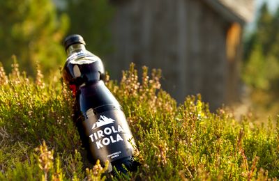 Flasche Tirola Kola liegend auf Bergwiese