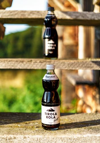 Glasflaschen Tirola Kola auf Holztreppe eines Almstadels